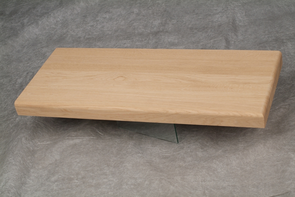 Blat dębowy o jasnym odcieniu, wsparty na niewidocznej szklanej podstawie, ukazujący delikatny rysunek słojów drewna na gładkiej powierzchni.